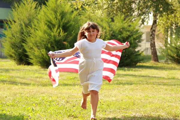 Chica sosteniendo una gran bandera americana — Foto de Stock