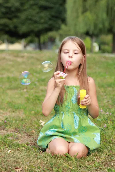 Cute little girl is blowing a soap bubble — Stock Photo, Image