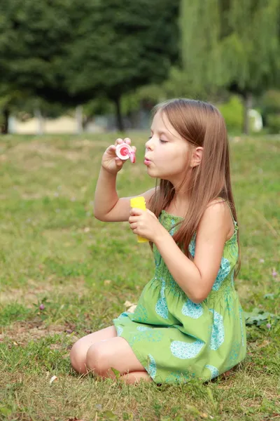 Menina bonito está soprando uma bolha de sabão — Fotografia de Stock