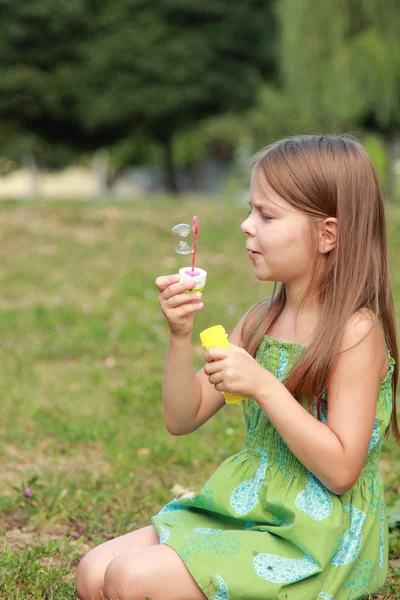 Söt liten flicka blåser en såpbubbla — Stockfoto