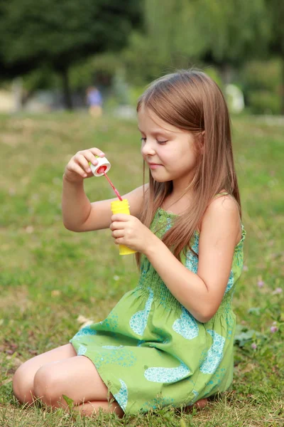 Klein meisje in het park met zeepbellen spelen — Stockfoto