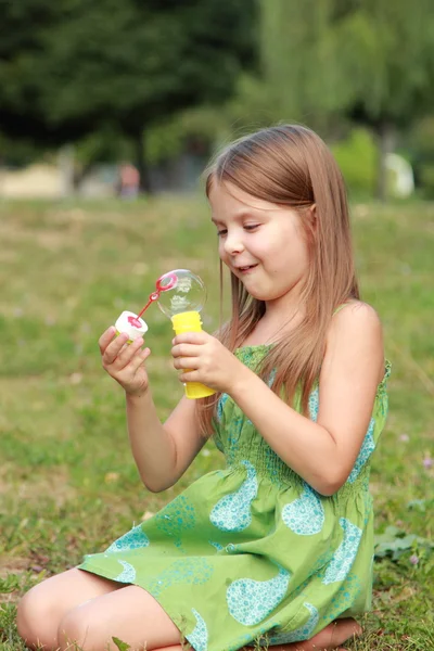 Linda niña está soplando una burbuja de jabón —  Fotos de Stock