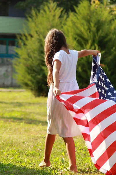 女孩抱着一个大型美国国旗 — 图库照片