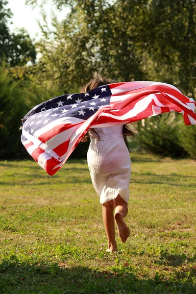 Fille tenant un grand drapeau américain — Photo