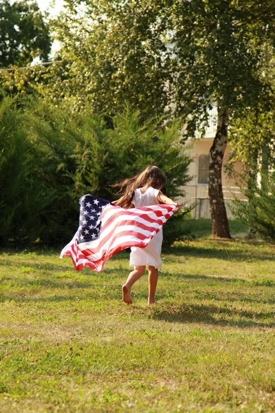 Flicka som håller en stor amerikansk flagga — Stockfoto