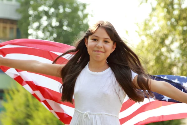 Joyeux jolie jeune fille tenant un grand un drapeau américain — Photo