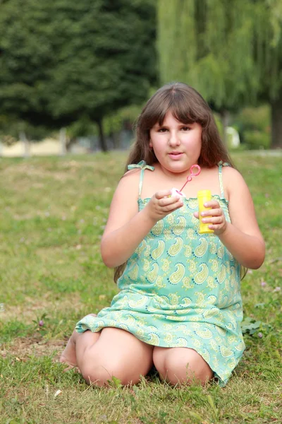 Kleines Mädchen spielt im Park mit Seifenblasen — Stockfoto