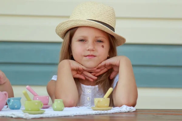Маленькая девочка играет с игрушечными тарелками для чая — стоковое фото