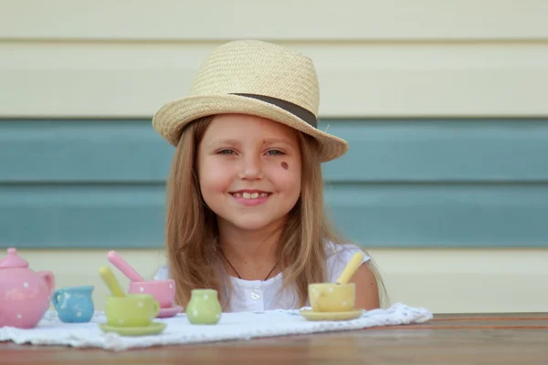 Маленькая девочка играет с игрушечными тарелками для чая — стоковое фото