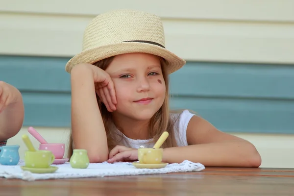 Klein meisje spelen met speelgoed gerechten voor thee — Stockfoto