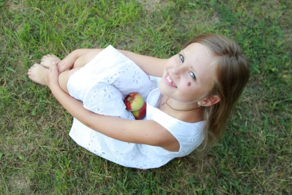 Chica en un vestido blanco sosteniendo manzanas — Foto de Stock