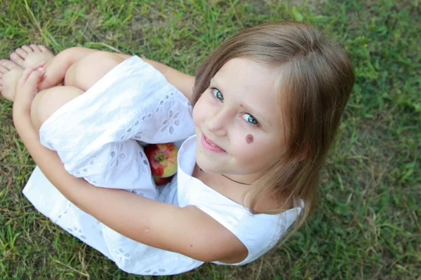 Liten flicka sitter på gräset — Stockfoto