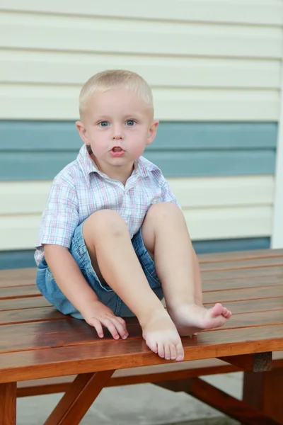 Kind klom met zijn voeten op de tafel — Stockfoto