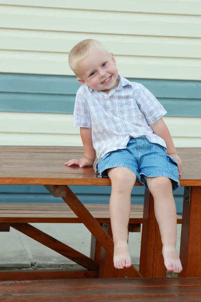 Kind klom met zijn voeten op de tafel — Stockfoto