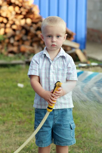 Kleiner Junge wässert den Rasen — Stockfoto
