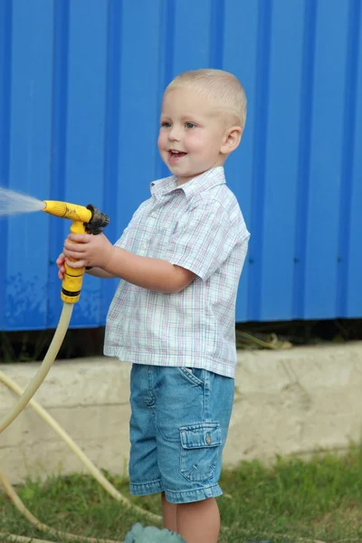 Kleiner Junge wässert den Rasen — Stockfoto
