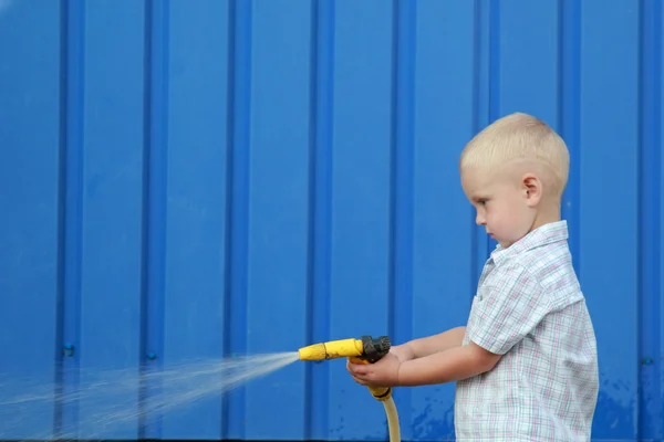 Little blond boy watering the lawn — Stock Photo, Image