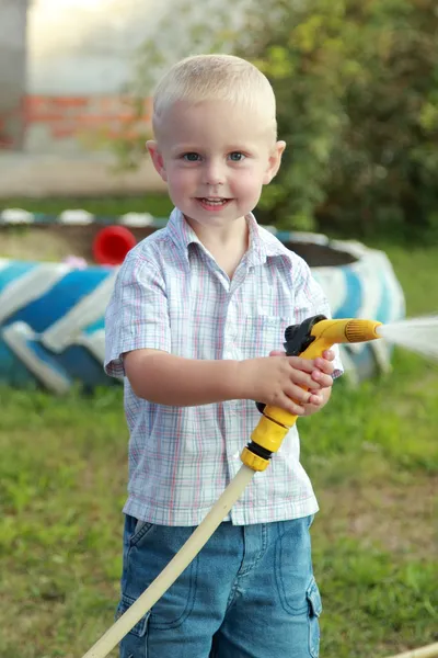 Mały chłopiec blond, podlewanie trawnika — Zdjęcie stockowe