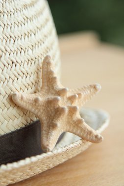 Yaz hasır şapka ve küçük bir deniz yıldızı ahşap arka plan