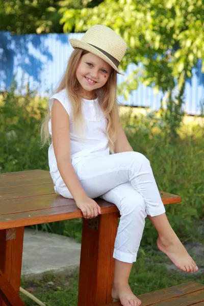 Little blond girl sitting on a bench — Stock Photo, Image