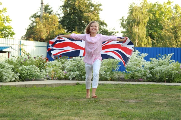 Allegro bella ragazza in esecuzione con la bandiera del Regno Unito — Foto Stock