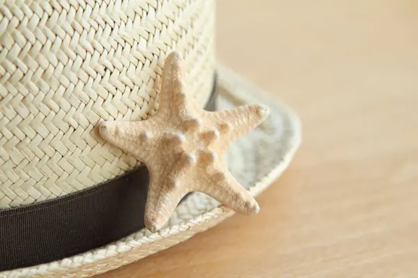 Summer straw hat and a little starfish wooden background — Stock Photo, Image