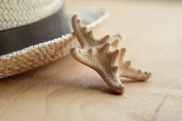 Chapeau de paille et étoile de mer sur fond en bois — Photo