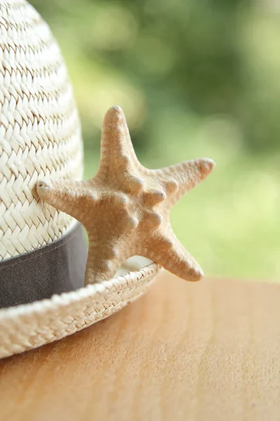 Straw hat and a little starfish blurred background — Stock Photo, Image