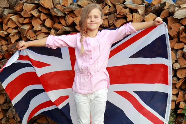 European smiling little girl holding a big UK flag outdoors Royalty Free Stock Photos