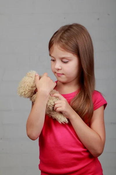Маленькая девочка обнимает медвежью игрушку — стоковое фото