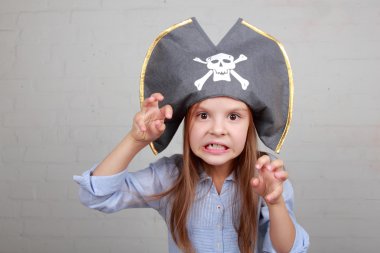 verschrikkelijke piraat meisje in shirt en hoed op een grijze achtergrond