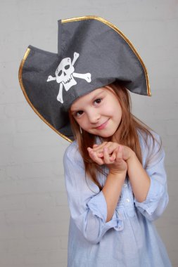 verschrikkelijke piraat meisje in shirt en hoed op een grijze achtergrond