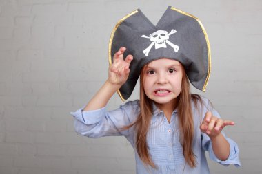 verschrikkelijke piraat meisje in shirt en hoed op een grijze achtergrond