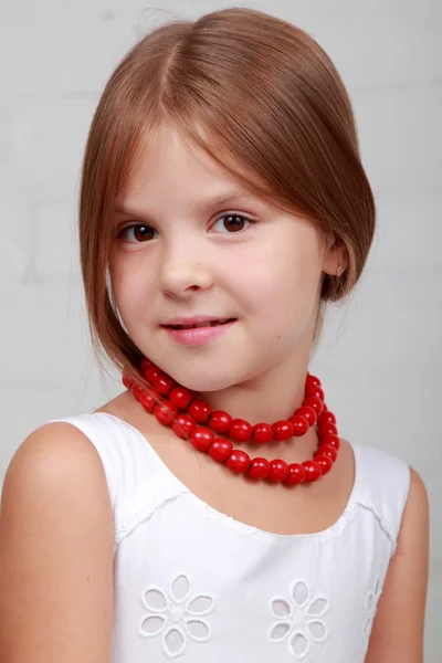 Bild eines schönen Mädchens mit roten Perlen — Stockfoto