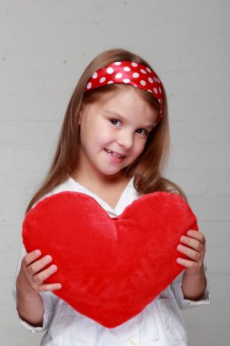 küçük kız büyük bir kırmızı kalp tutar