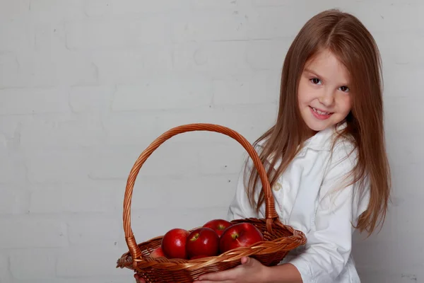 Девушка держит плетеную корзину с яблоками — стоковое фото