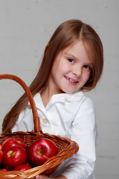 Menina segurando cesta de vime com maçãs — Fotografia de Stock