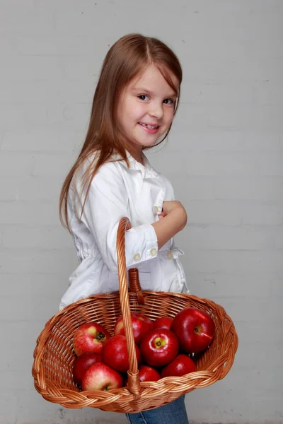 Fille tenant panier en osier avec des pommes — Photo