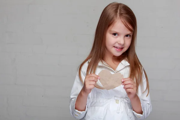 Menina segurando um pequeno coração de papel — Fotografia de Stock