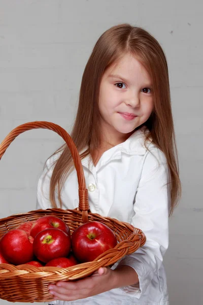 Flicka anläggning korg med äpplen — Stockfoto