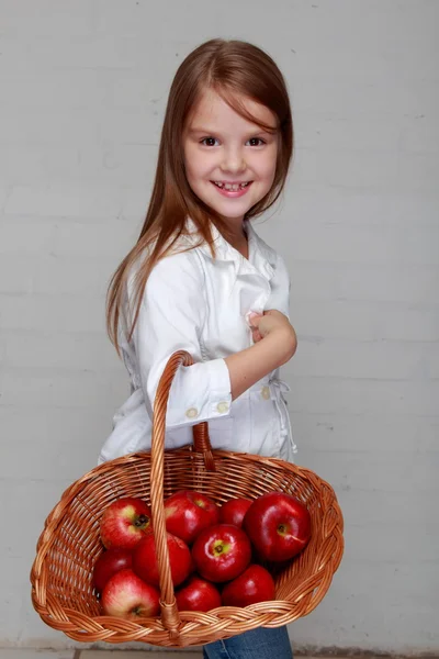 Menina segurando cesta de maçãs — Fotografia de Stock