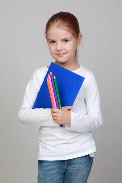 Flicka som håller i en mapp och pennor — Stockfoto