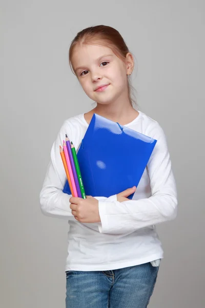 Flicka hållande en blå mapp och pennor — Stockfoto