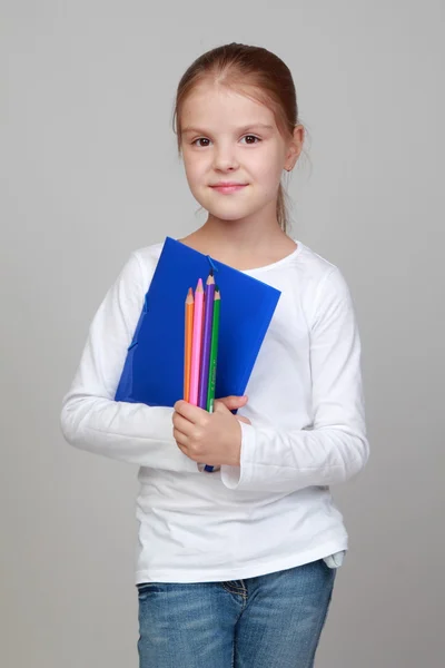 Chica sosteniendo una carpeta azul y lápices —  Fotos de Stock