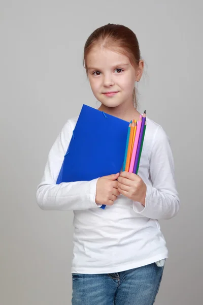 Flicka hållande en blå mapp och pennor — Stockfoto