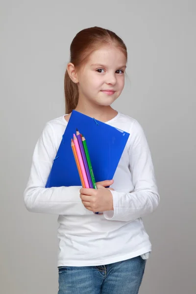 Flicka hållande en blå mapp och pennor — Stockfoto