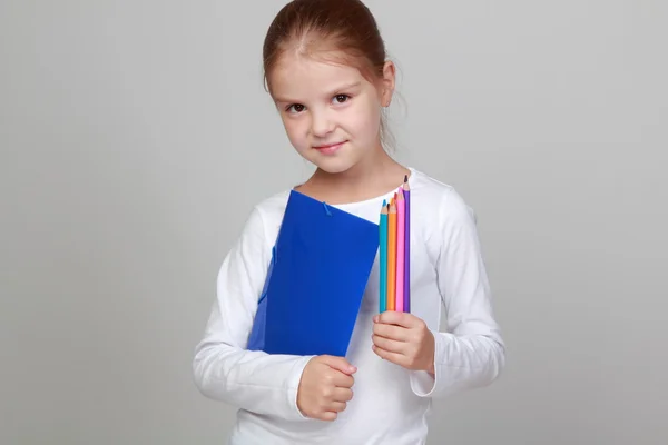 Menina segurando uma pasta azul e lápis — Fotografia de Stock