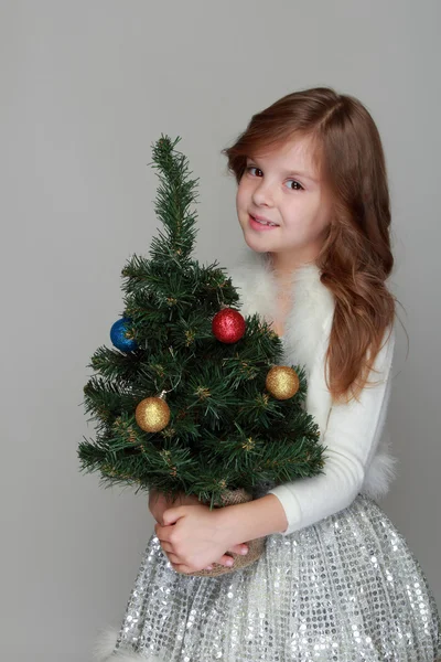 Girl holding a small Christmas tree — Stock Photo, Image