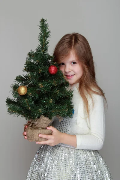 Flicka som håller en liten julgran — Stockfoto