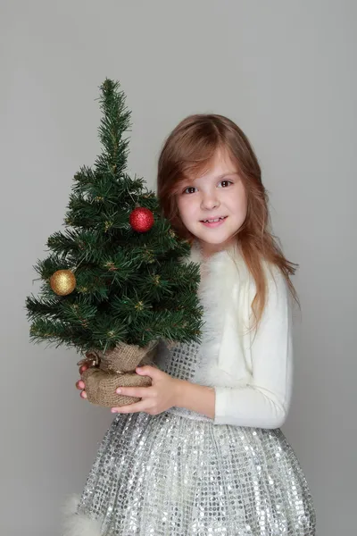 Menina segurando uma pequena árvore de Natal — Fotografia de Stock